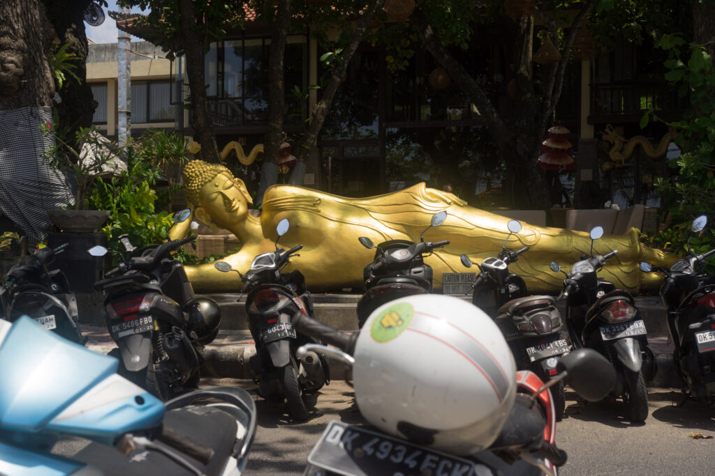 A sleeping Buddha enhancing the scooter parking of Kuta