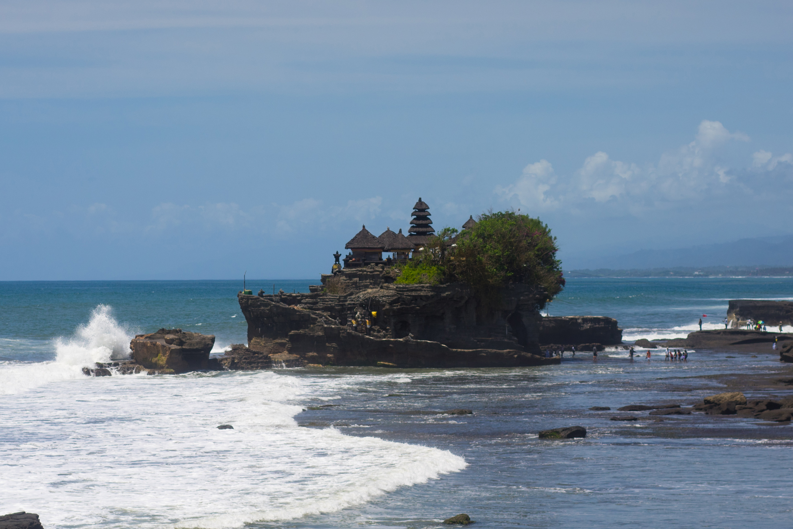 Waves splash up against Tanah Lot at low tide