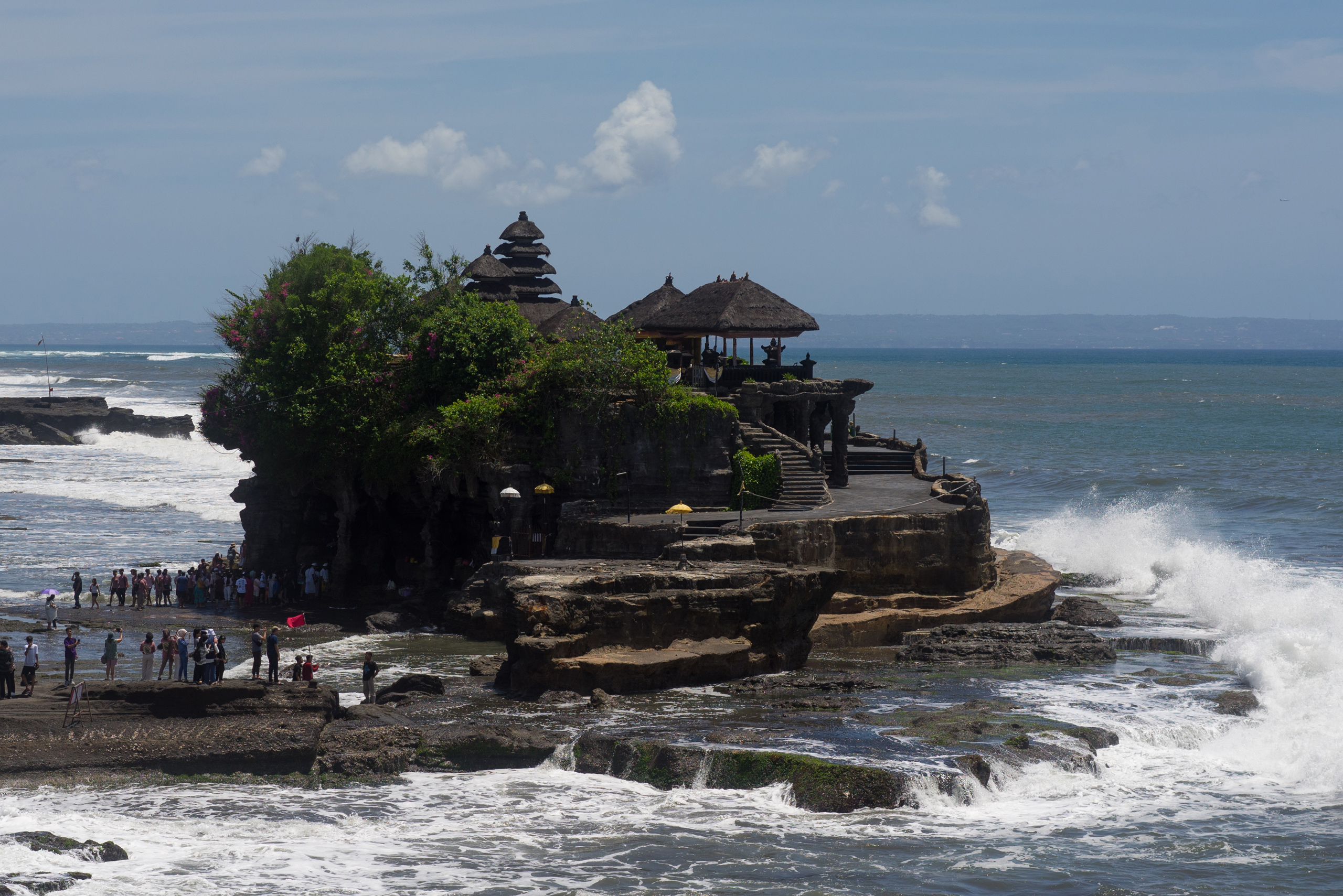 Waves splash up against Tanah Lot at low tide