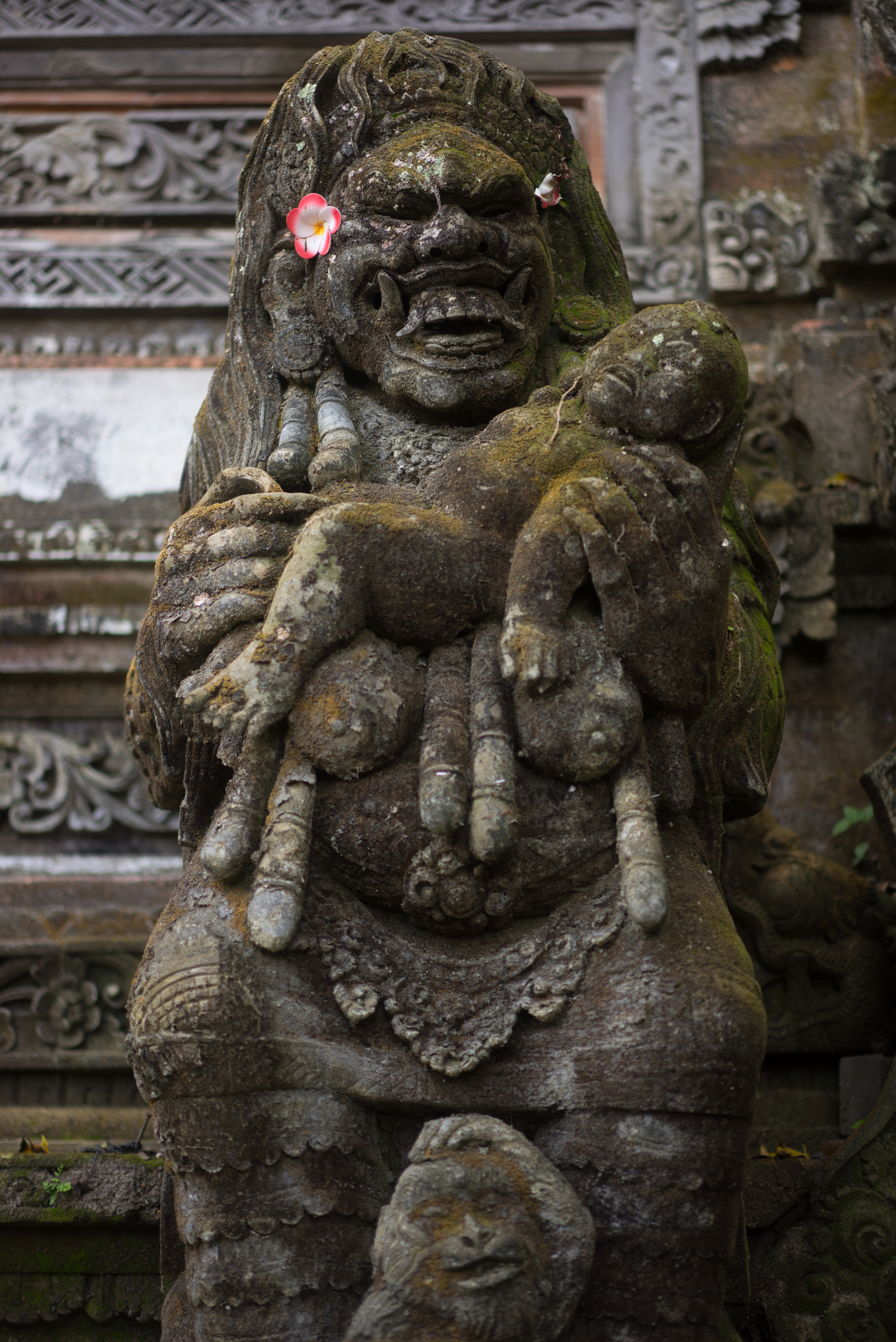 A Rangda holds up a crying baby while it thinks about eating it and a monkey shields his head