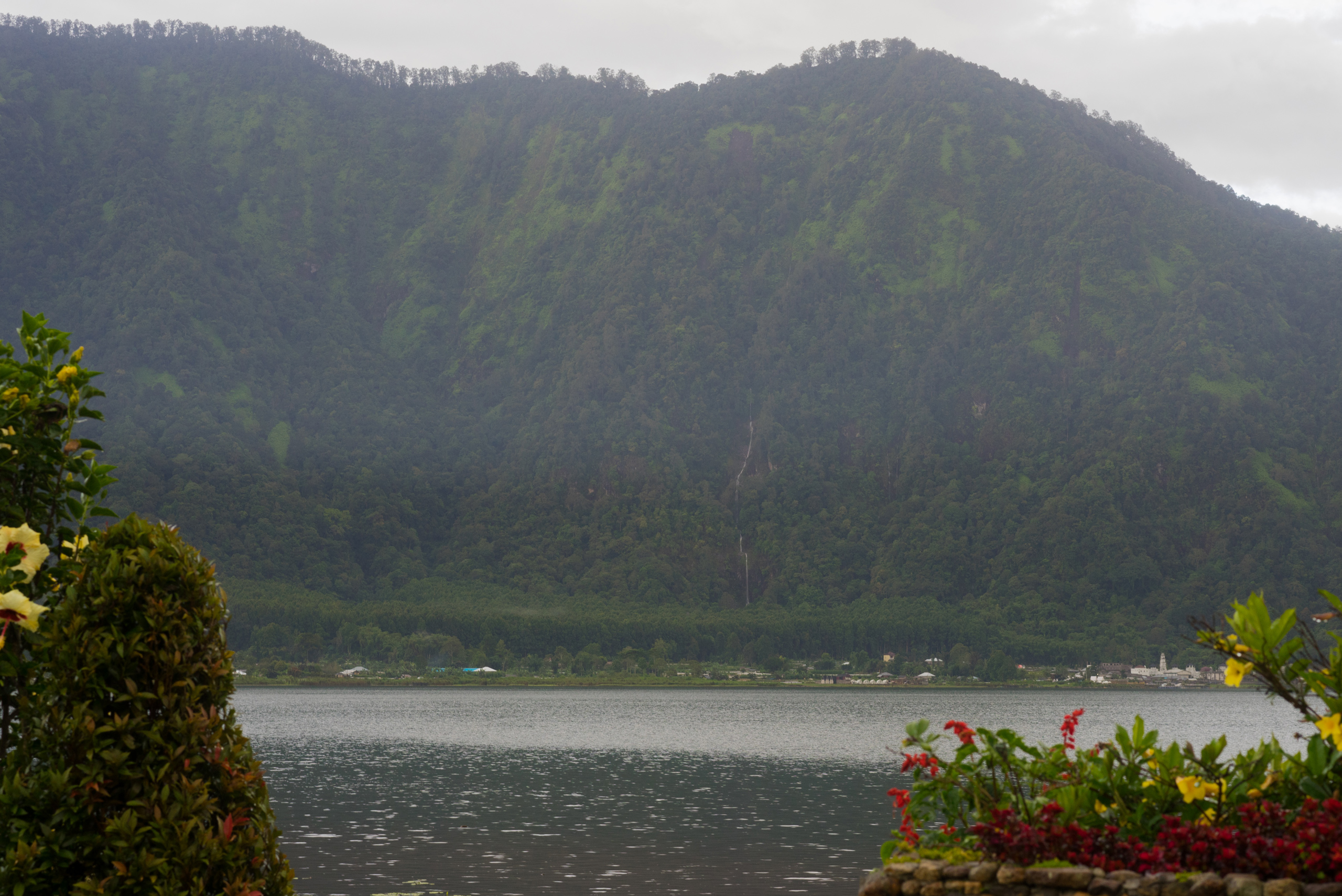 A waterfall seen running down the mountain on the other side of the lake