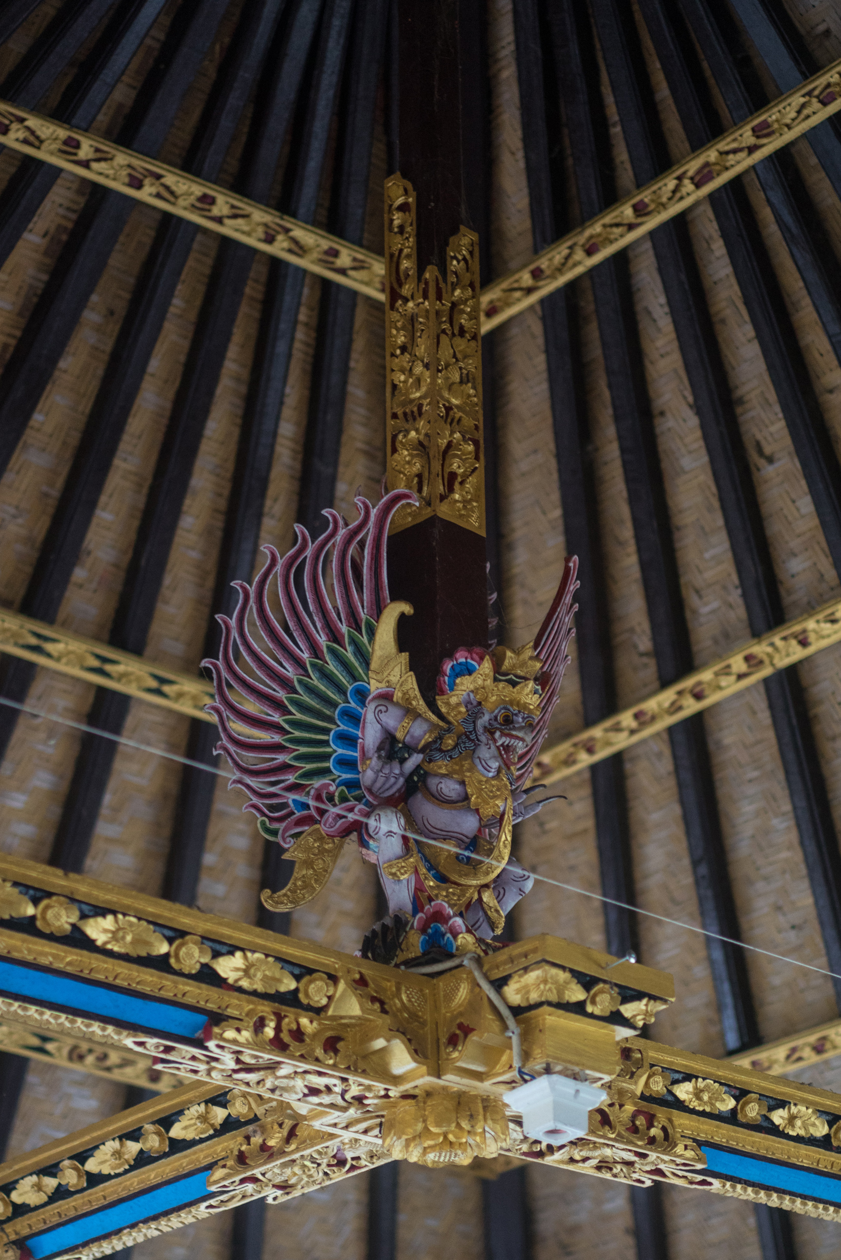 A Garuda hangs up in the rafters looking down on those who enter it